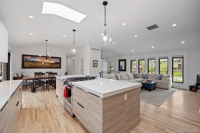 kitchen featuring modern cabinets, light wood-style flooring, a spacious island, and high end range