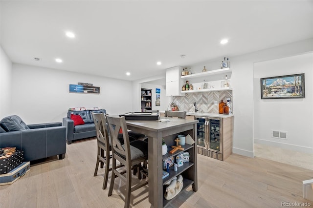 dining space with visible vents, wine cooler, recessed lighting, bar, and light wood finished floors