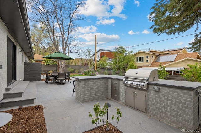 view of patio / terrace with outdoor dining area, a fenced backyard, exterior kitchen, and a grill