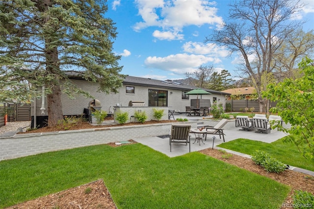 rear view of property with a lawn, a patio, and fence