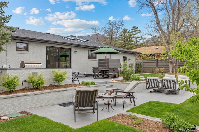 rear view of house with exterior kitchen, brick siding, fence, a patio, and outdoor dining space