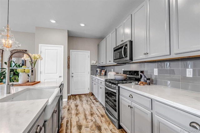 3778 Happyheart Way, Castle Rock, CO 80109 - kitchen featuring stainless steel appliances, light wood finished floors, tasteful backsplash, light countertops, and pendant lighting