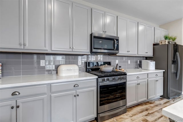 3778 Happyheart Way, Castle Rock, CO 80109 - kitchen with appliances with stainless steel finishes, light wood-style floors, decorative backsplash, light countertops, and white cabinets