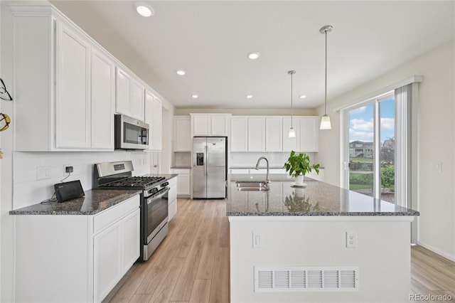 12854 Clearview St, Firestone, CO 80504 - kitchen with stainless steel appliances, white cabinetry, a kitchen island with sink, recessed lighting, and light wood finished floors
