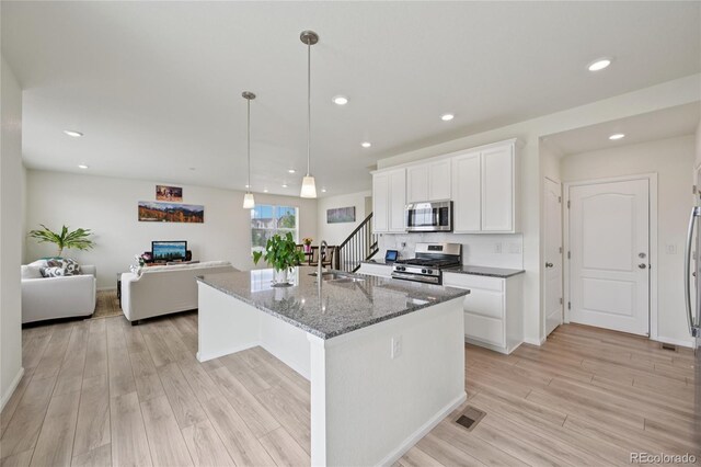 12854 Clearview St, Firestone, CO 80504 - kitchen featuring stainless steel appliances, light wood finished floors, white cabinetry, stone counters, and recessed lighting