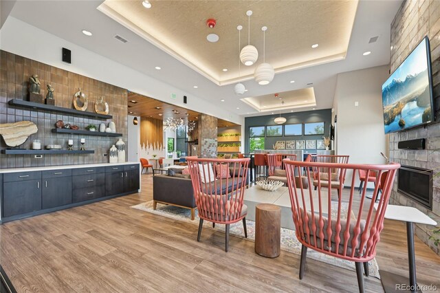 12854 Clearview St, Firestone, CO 80504 - bar area with a raised ceiling, light wood-style floors, recessed lighting, a large fireplace, and pendant lighting