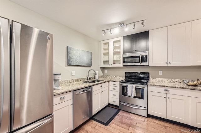 kitchen featuring light wood-type flooring, track lighting, white cabinetry, sink, and stainless steel appliances