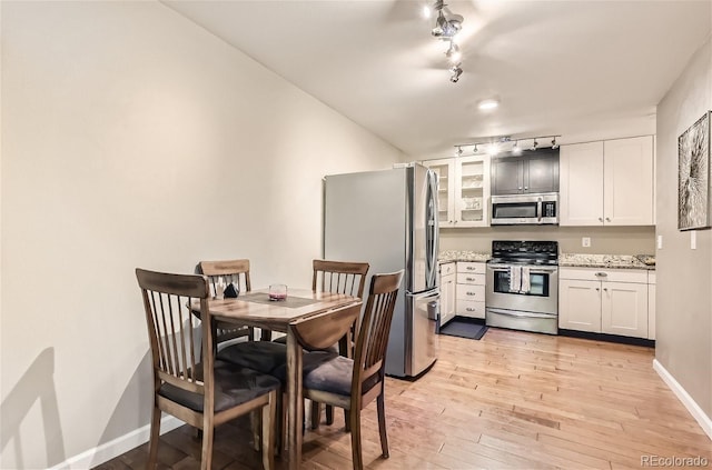 dining room with light hardwood / wood-style floors and track lighting