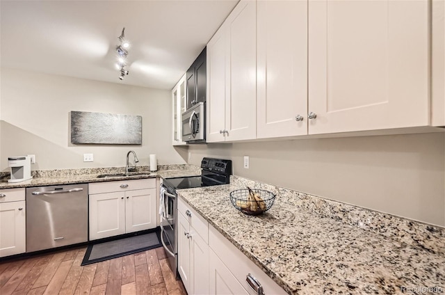 kitchen with sink, light hardwood / wood-style floors, track lighting, white cabinetry, and stainless steel appliances