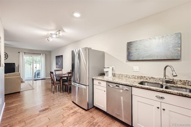 kitchen with stainless steel appliances, sink, light wood-type flooring, white cabinets, and track lighting