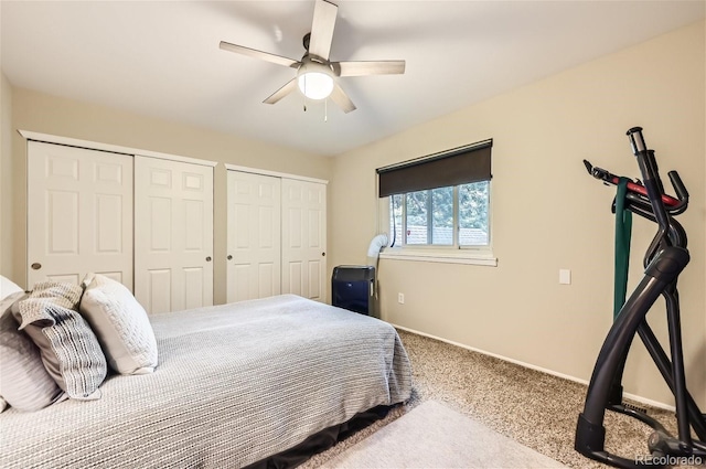 bedroom with ceiling fan, two closets, and carpet