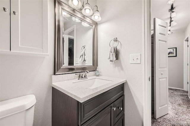 bathroom with track lighting, toilet, and vanity