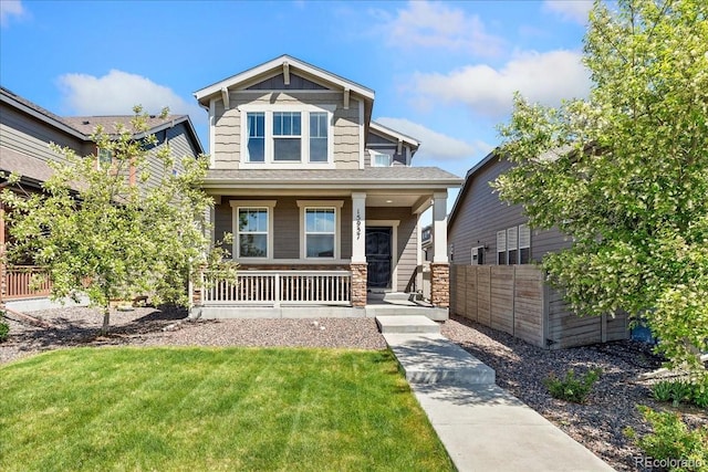 craftsman inspired home with a porch, fence, and a front yard