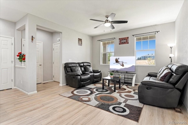 living area featuring baseboards, a ceiling fan, and wood finished floors