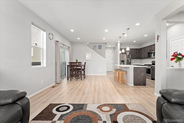 living area with light wood-type flooring, recessed lighting, and baseboards