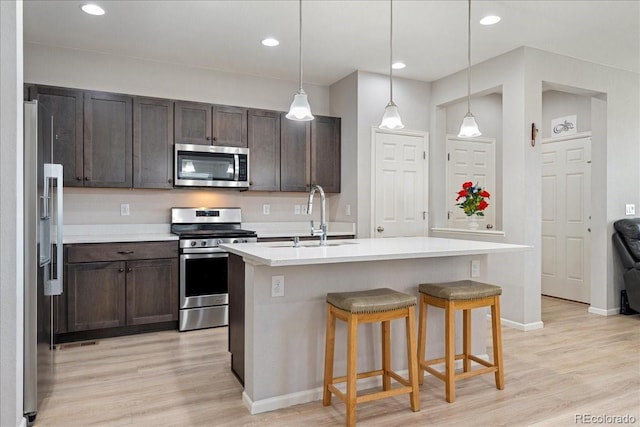 kitchen featuring a sink, dark brown cabinetry, stainless steel appliances, and light wood-type flooring