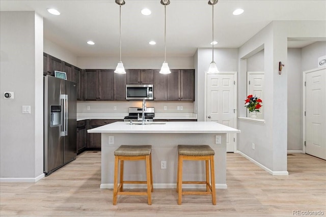 kitchen with dark brown cabinets, light countertops, a sink, light wood-style flooring, and stainless steel appliances