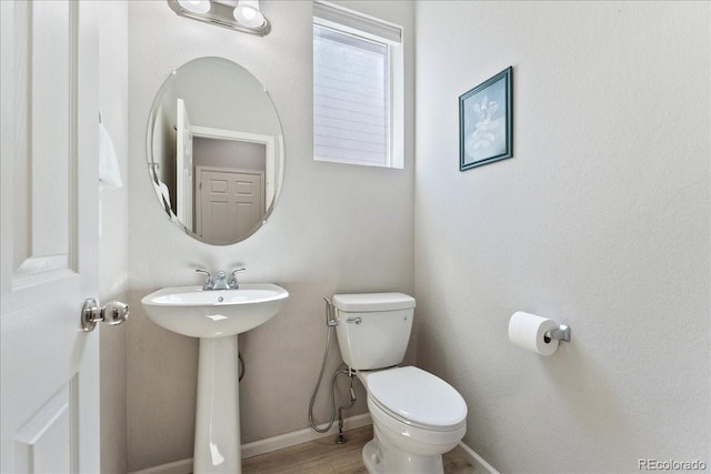 bathroom with baseboards, a sink, wood finished floors, and toilet