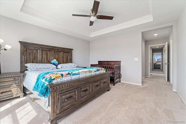 bedroom featuring crown molding, a tray ceiling, light carpet, and baseboards