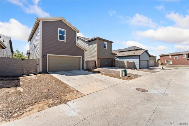 traditional home featuring concrete driveway, fence, a gate, and a garage
