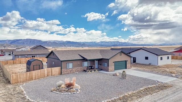 view of front of house with driveway, a garage, fence, and a mountain view