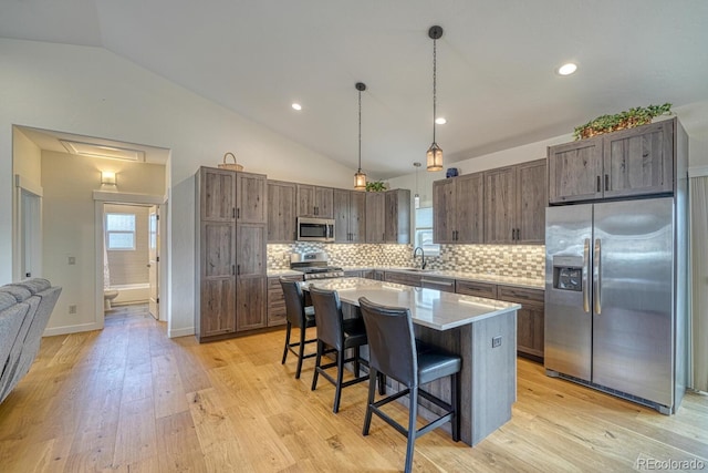 kitchen featuring stainless steel appliances, a breakfast bar, a sink, and light wood finished floors