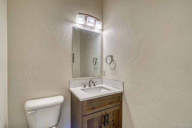 half bathroom featuring vanity and a textured wall