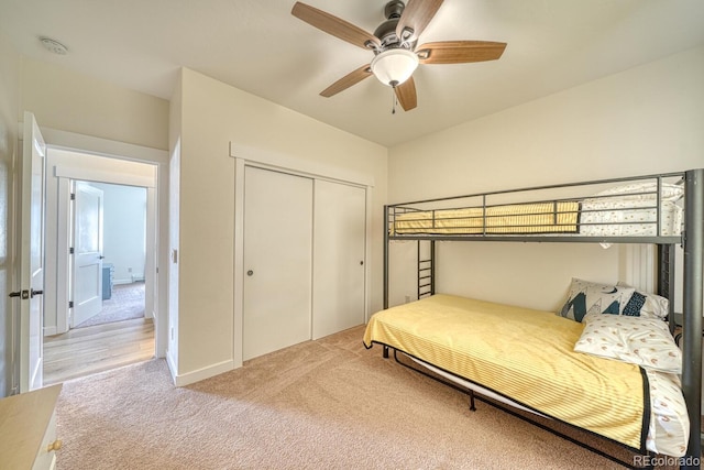 bedroom with light carpet, ceiling fan, and a closet