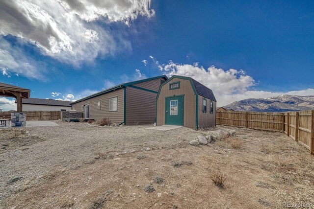 back of house featuring a fenced backyard, a shed, a mountain view, and an outdoor structure