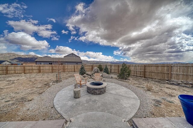 view of patio / terrace with an outdoor fire pit, a fenced backyard, and a mountain view