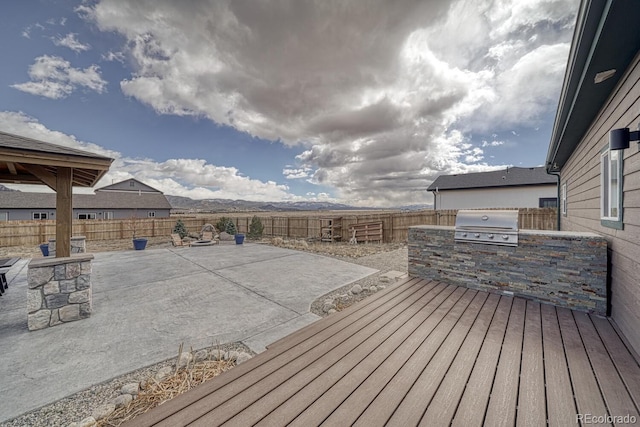 wooden terrace with a patio, exterior kitchen, a fenced backyard, and a grill