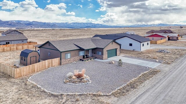 single story home with driveway, stone siding, fence, and a mountain view