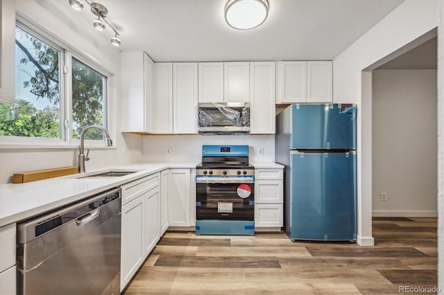 kitchen with light hardwood / wood-style flooring, appliances with stainless steel finishes, white cabinetry, and sink