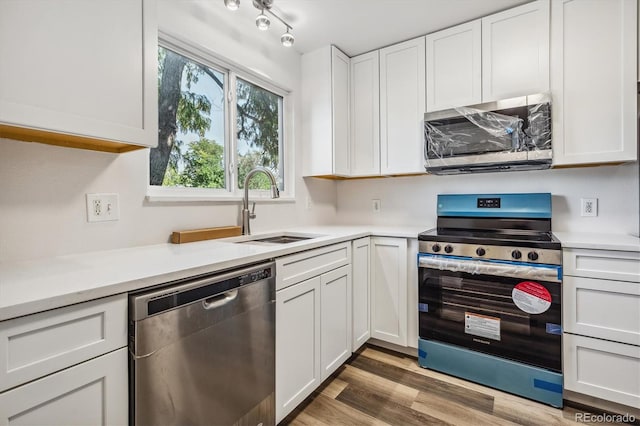 kitchen with light wood-type flooring, white cabinets, stainless steel appliances, and sink