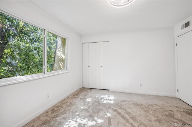 unfurnished bedroom with light colored carpet and a closet