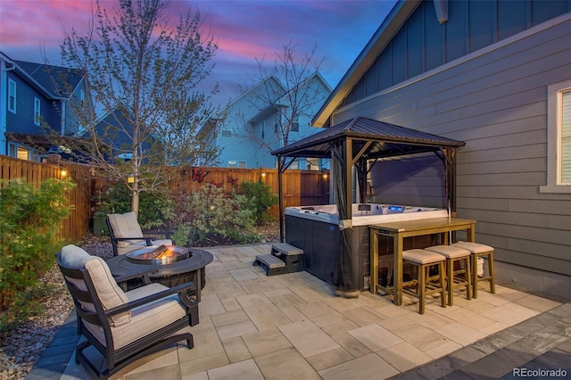 8444 E 55th Pl, Denver, CO 80238 - patio terrace at dusk featuring a fenced backyard, a gazebo, a hot tub, and a fire pit