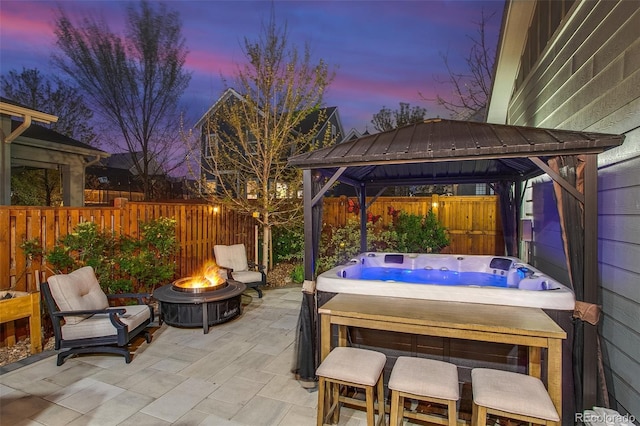8444 E 55th Pl, Denver, CO 80238 - patio terrace at dusk featuring a hot tub, a gazebo, a fenced backyard, and an outdoor fire pit