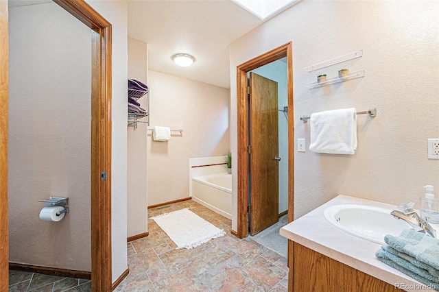 12261 N Holly Way, Brighton, CO 80602 - full bath with a garden tub, vanity, baseboards, and stone finish floors