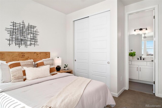 bedroom with ensuite bathroom, carpet flooring, sink, and a closet