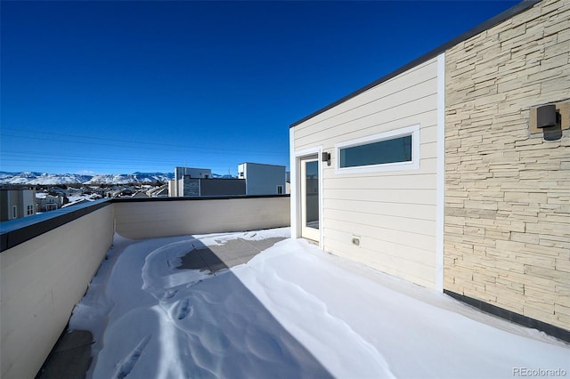 snow covered patio featuring a mountain view and a balcony