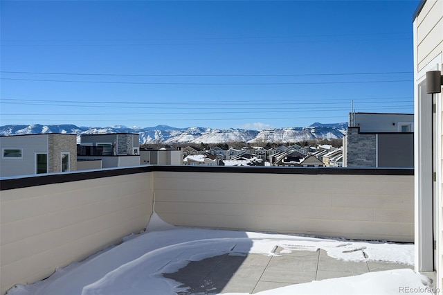 snow covered patio featuring a balcony and a mountain view