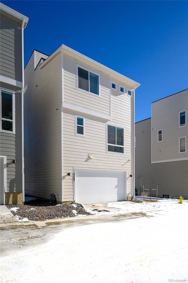 snow covered house featuring a garage