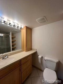 bathroom featuring vanity, toilet, tile patterned floors, and a shower with shower door