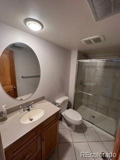 bathroom featuring tile patterned flooring, walk in shower, vanity, and toilet