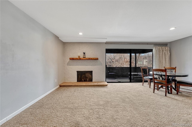 living room with carpet, a fireplace with raised hearth, baseboards, and recessed lighting