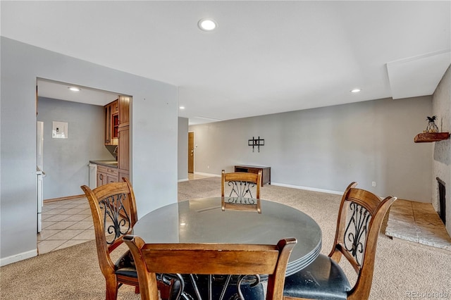 dining space featuring light carpet, light tile patterned floors, baseboards, a fireplace with raised hearth, and recessed lighting