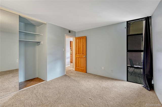 unfurnished bedroom with carpet floors, a closet, and visible vents