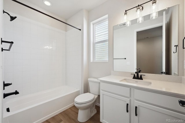 full bathroom featuring vanity, hardwood / wood-style floors, tiled shower / bath combo, and toilet