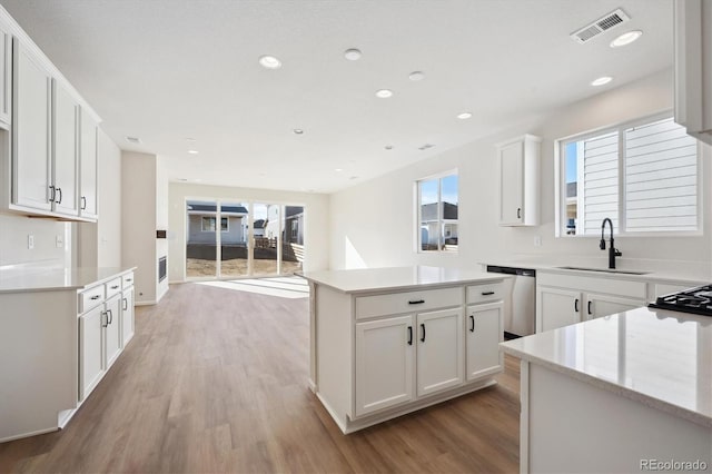 kitchen with stainless steel dishwasher, a center island, sink, and white cabinets