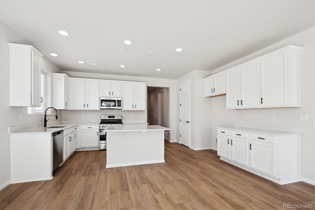 kitchen featuring white cabinetry, appliances with stainless steel finishes, a center island, and sink